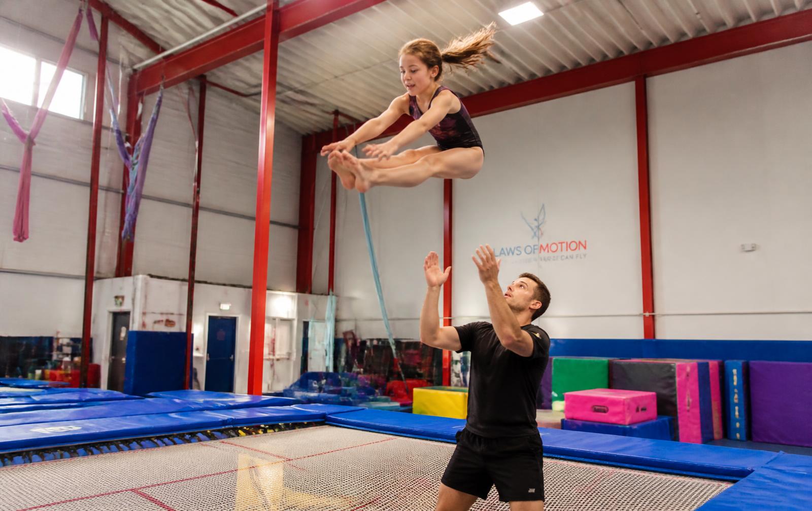 A coach spotting an athlete at the Defy Gravity training gym
